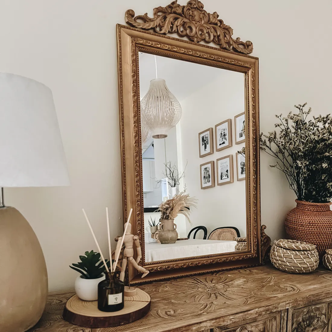 A Pristine reed diffuser on a carved wooden console beneath an ornate mirror